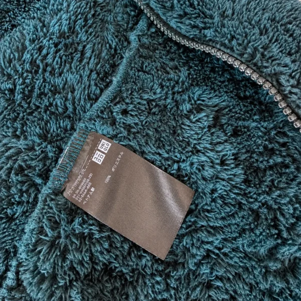 นกฮุก ริมโขง Online Store ซูมใกล้เนื้อผ้าฟลีซสีทีลพร้อมป้ายยูนิโคล่ เสื้อแจ็คเก็ต ซิปหน้า ผ้าฟลีซ ขนนุ่ม UNIQLO